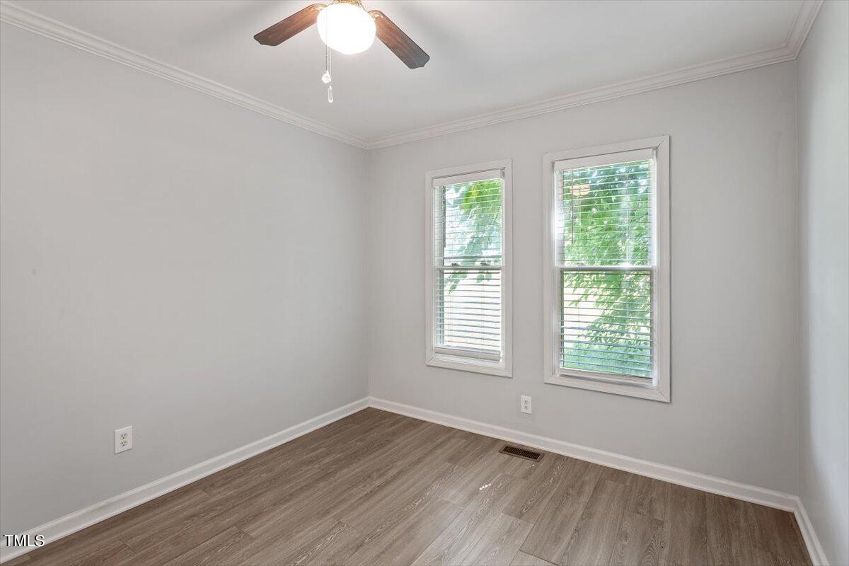 2474 Sumter Drive Garner, NC 27529 - Photo 22 of 27 an empty room with wooden floor exposed radiator and windows