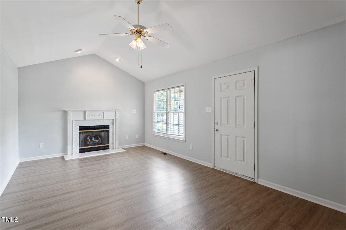 2474 Sumter Drive Garner, NC 27529 - Photo 7 of 27 an empty room with wooden floor fireplace and windows