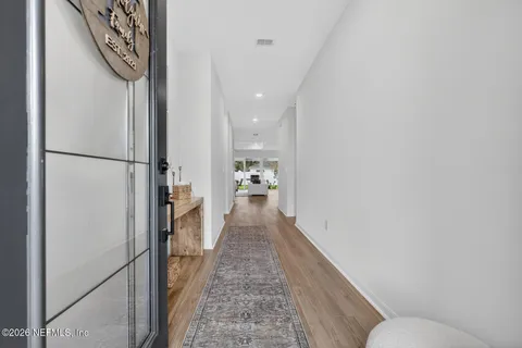 a hallway with wooden floor electronic appliances and stairs