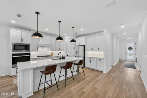 a living room with furniture a wooden floor and a kitchen view