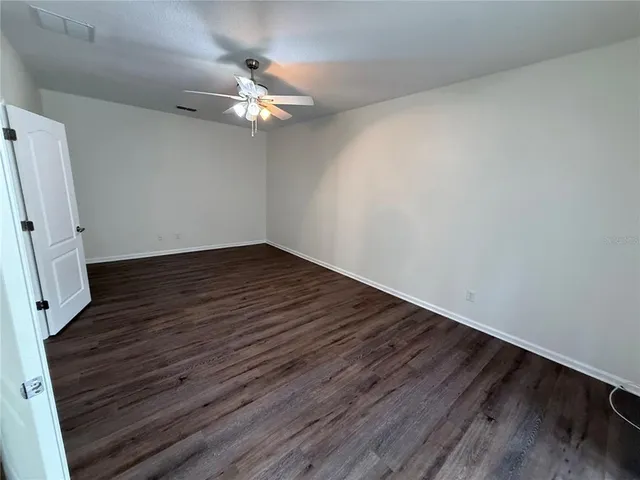 an empty room with a ceiling fan and window