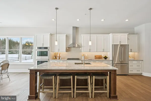 a kitchen with stainless steel appliances granite countertop a table chairs stove and refrigerator