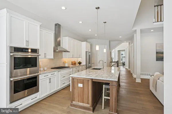 a kitchen with stainless steel appliances granite countertop a stove top oven a sink dishwasher a dining table and chairs with wooden floor