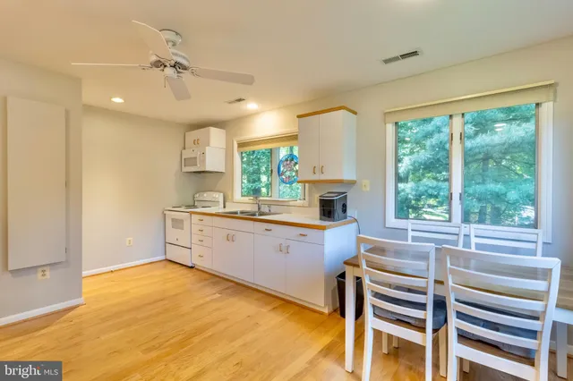 a large white kitchen with wooden floor and a window