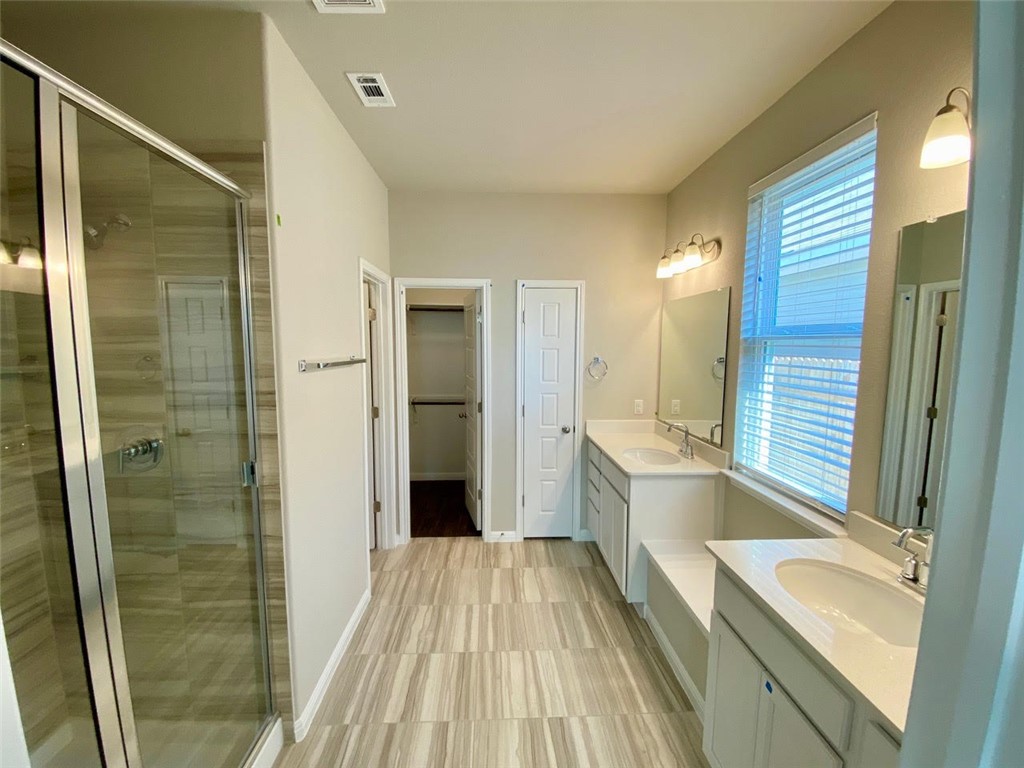 237 Michaelis Drive Leander, TX 78641 - Photo 12 of 23 a bathroom with a tub sink shower and two mirror