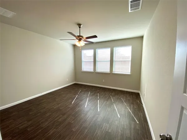an empty room with wooden floor fan and windows
