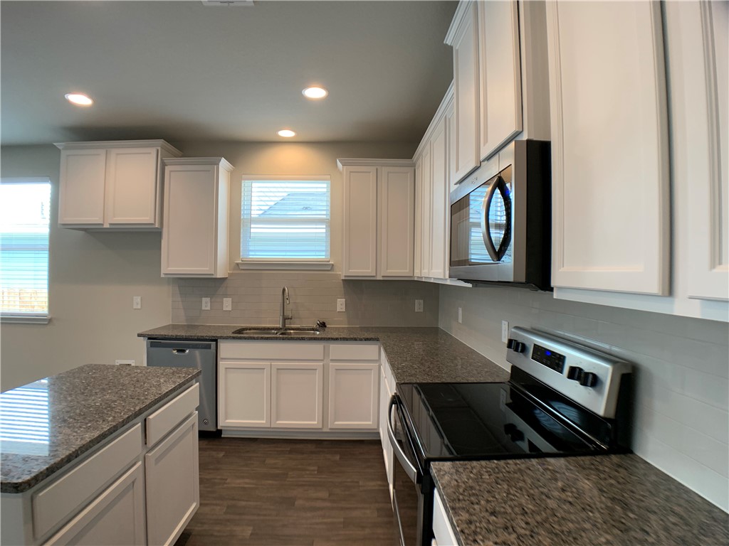 237 Michaelis Drive Leander, TX 78641 - Photo 3 of 23 a kitchen with granite countertop a sink a stove and cabinets