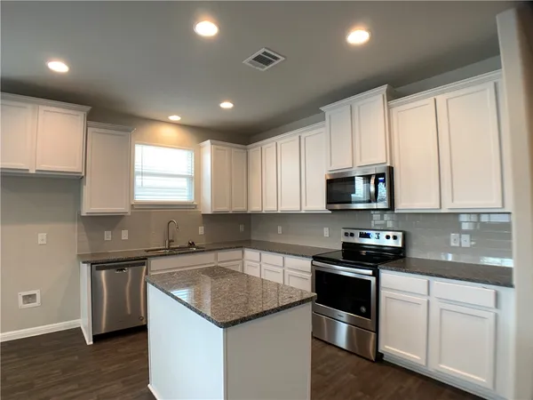 a kitchen with stainless steel appliances granite countertop a sink dishwasher a stove and a refrigerator