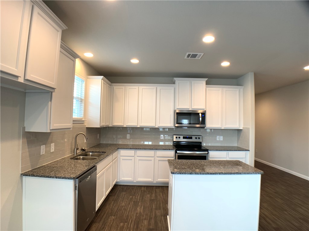 237 Michaelis Drive Leander, TX 78641 - Photo 6 of 23 a kitchen with granite countertop a stove top oven a sink a counter space and cabinets