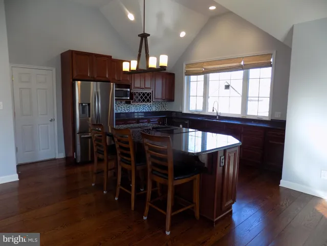 a kitchen with stainless steel appliances granite countertop a table chairs stove and refrigerator