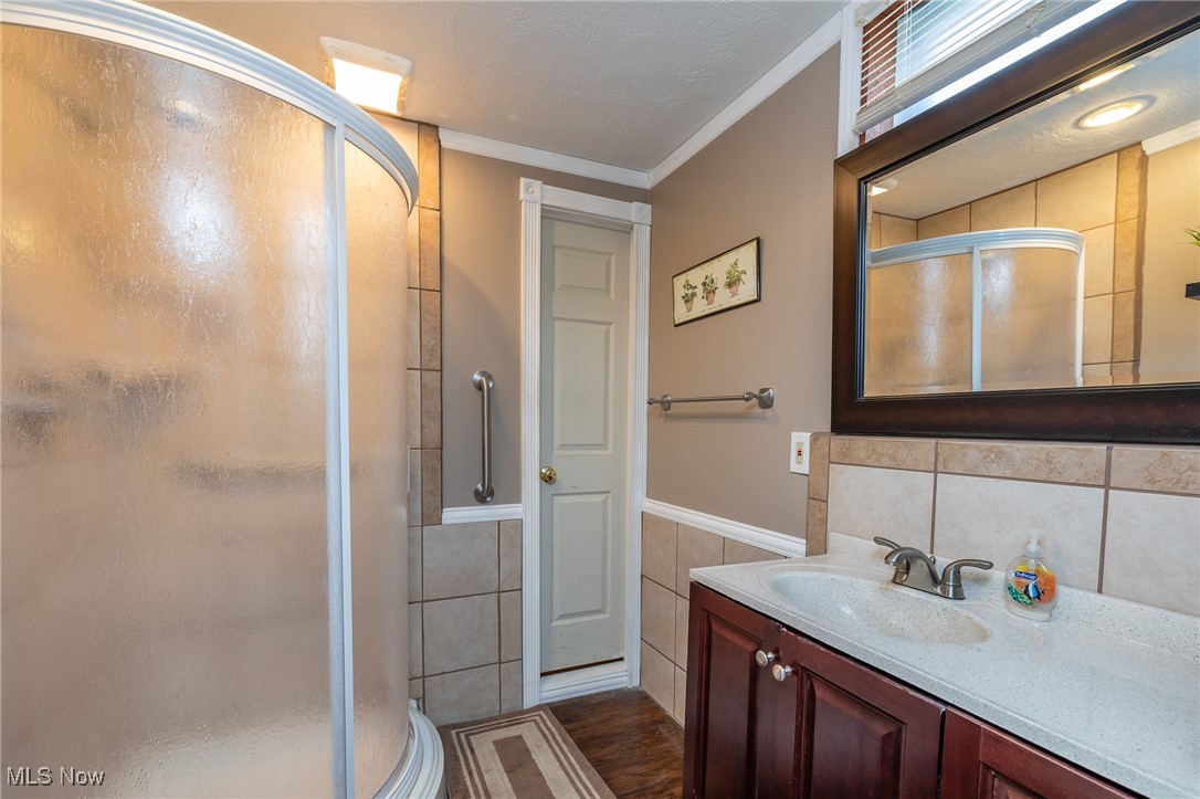 12181 Williams Road Homerville, OH 44235 - Photo 29 of 49 Bathroom with vanity, crown molding, walk in shower, and tile walls