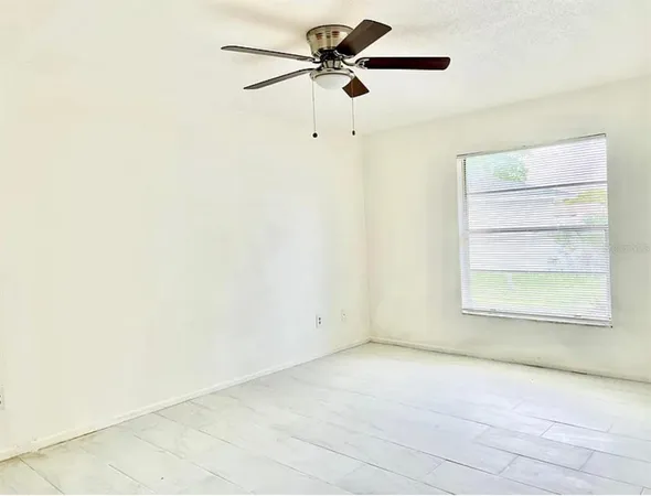 an empty room with a window and a ceiling fan