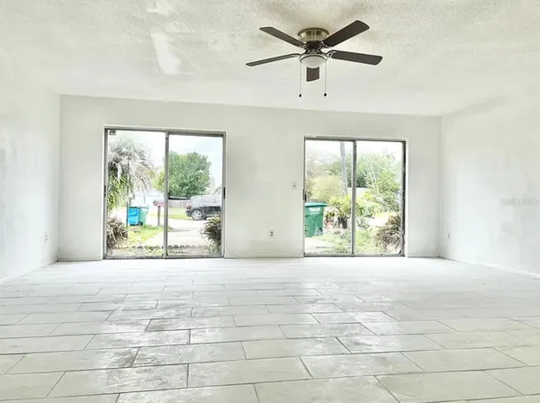 a view of an empty room with a window and a ceiling fan