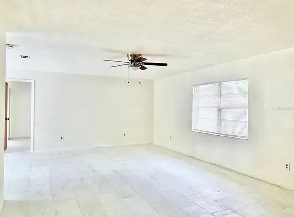 an empty room with a ceiling fan and a window