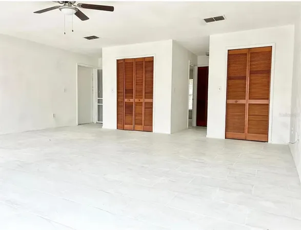 an empty room with windows and ceiling fan