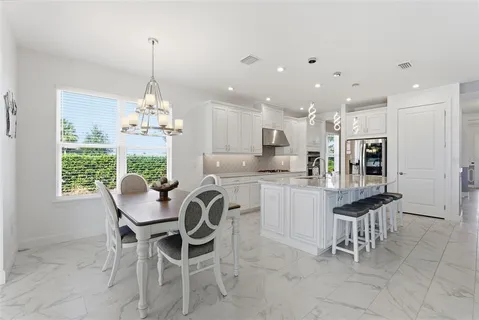 a kitchen with stainless steel appliances kitchen island granite countertop a dining table chairs and white cabinets