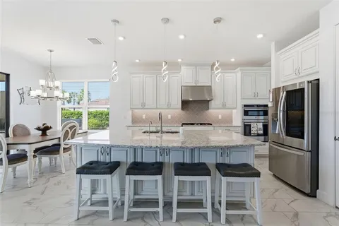 a kitchen with granite countertop stainless steel appliances a table and chairs in it