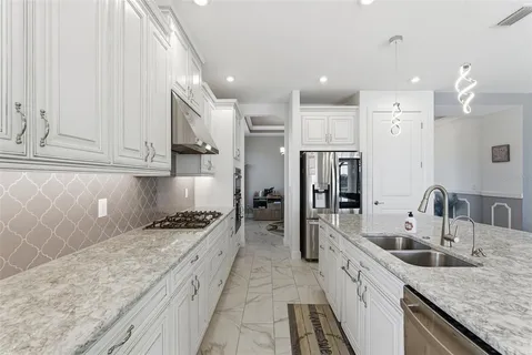 a kitchen with granite countertop a sink stainless steel appliances and cabinets