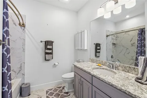 a bathroom with a granite countertop sink a toilet and a mirror