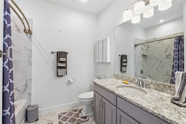 a bathroom with a granite countertop sink a toilet and a mirror