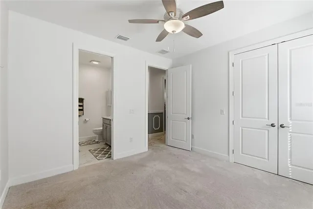 an empty room with closet and a chandelier fan