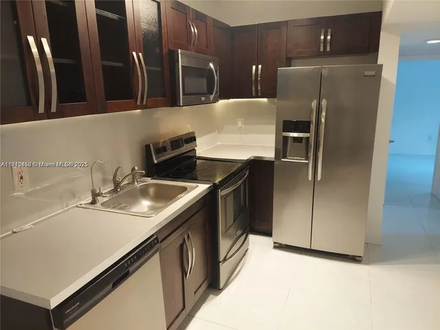 a kitchen with stainless steel appliances a sink a refrigerator and a cabinets