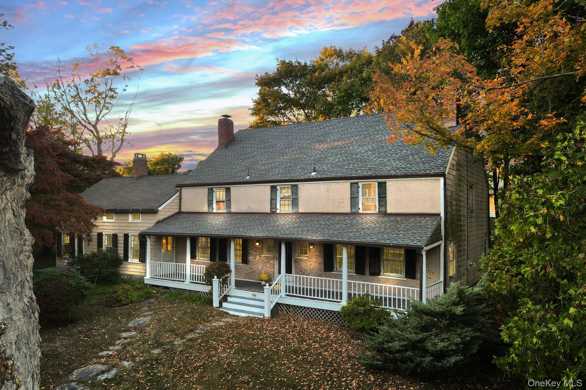 View of front of house featuring covered porch, roof with shingles, and a chimney