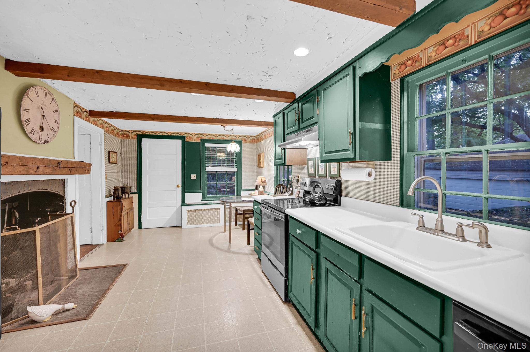 33 Ryder Road Ossining, NY 10562 - Photo 19 of 48 Kitchen featuring green cabinetry, stainless steel electric range, light countertops, beamed ceiling, and a fireplace