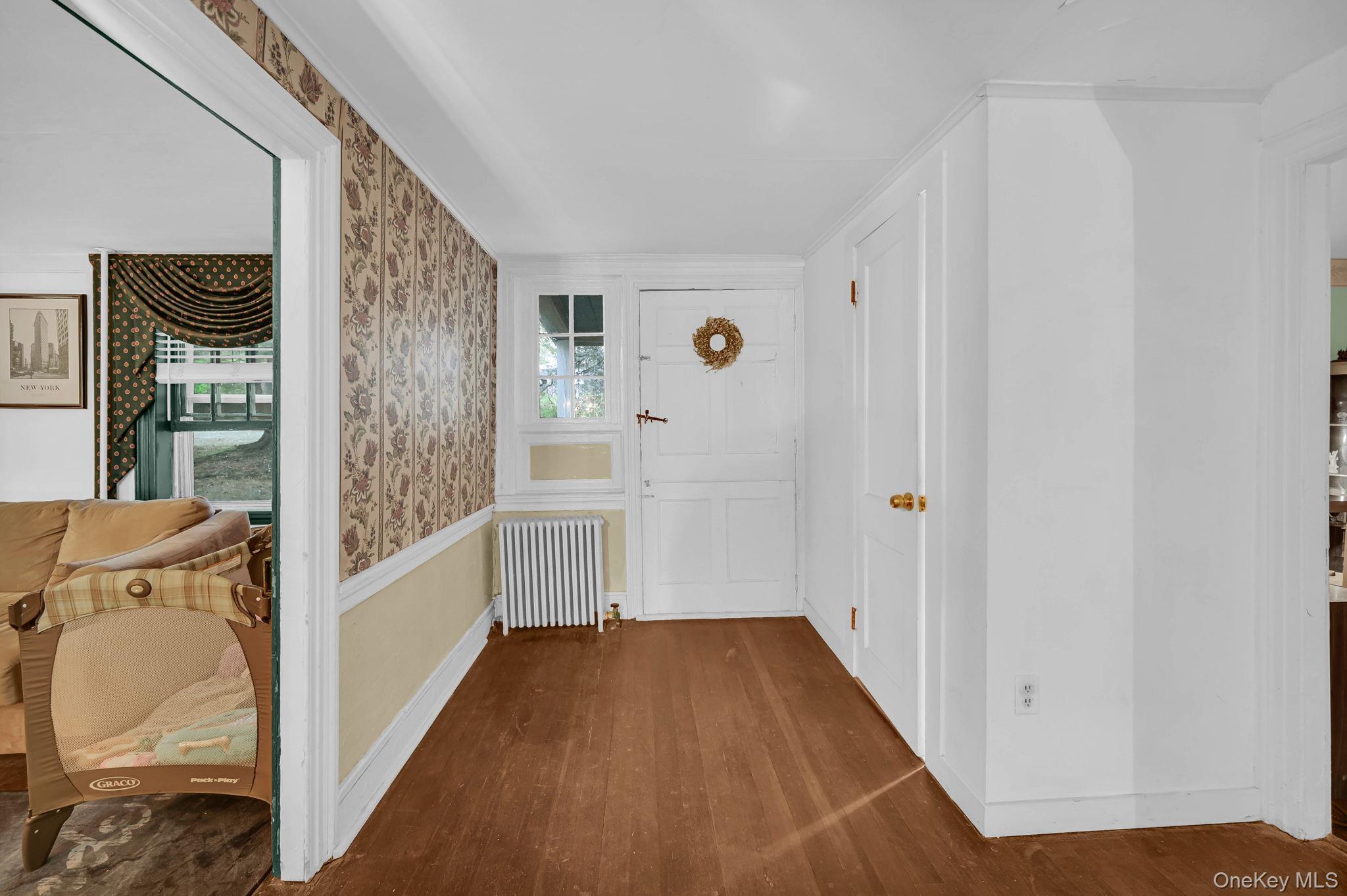 33 Ryder Road Ossining, NY 10562 - Photo 10 of 48 Entrance foyer featuring wallpapered walls, dark wood-style floors, radiator, and healthy amount of natural light
