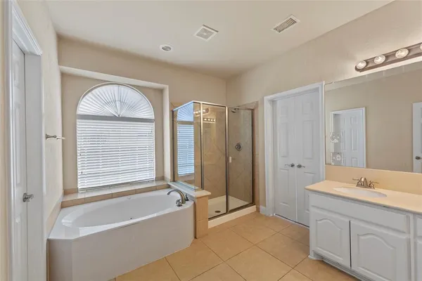 a spacious bathroom with a tub a double vanity sink a mirror and a shower