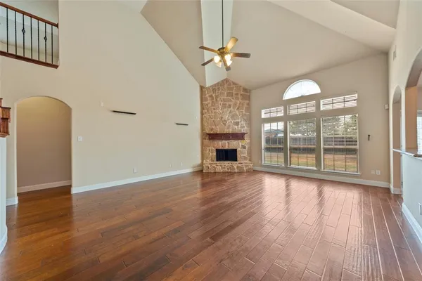 an empty room with wooden floor fan and windows