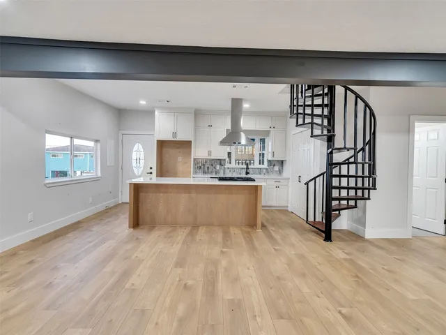 a living room with stainless steel appliances kitchen island hardwood floor and a window