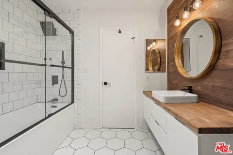 a bathroom with a granite countertop sink a mirror and shower
