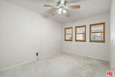 an empty room with windows and fan