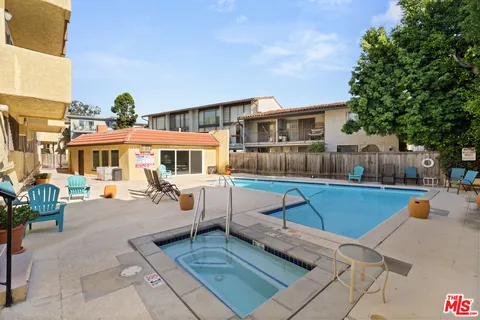 a view of a patio with couches table and chairs under an umbrella