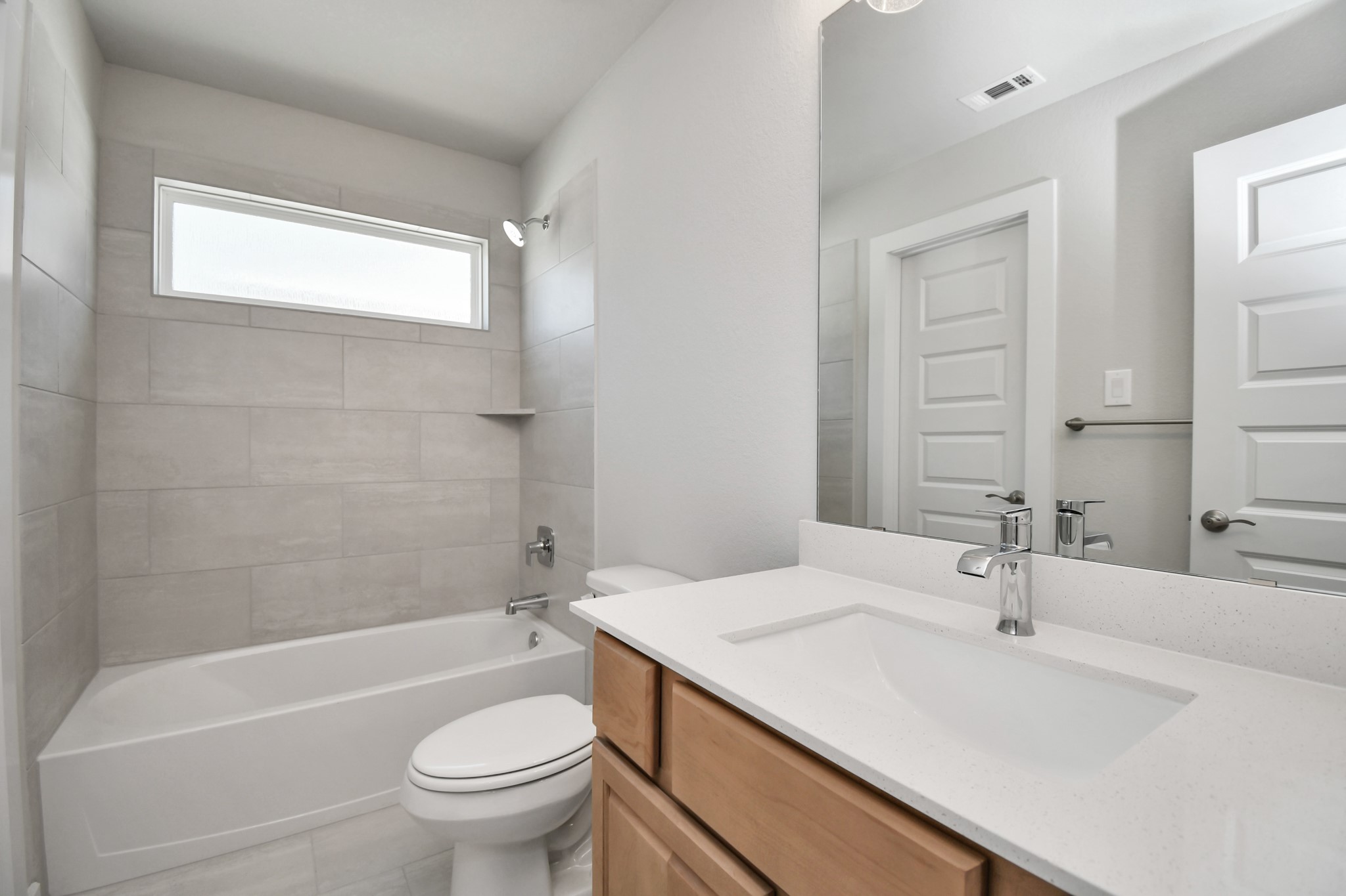 3106 Skerne Spring Dr Spring Spring, TX 77373 - Photo 34 of 47 Secondary bath features tile flooring, bath/shower combo with tile surround, light stained wood cabinets, beautiful light countertop.