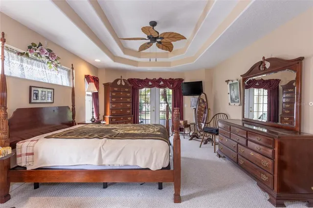 a spacious bedroom with a bed a chandelier and windows