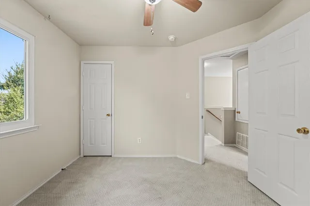 an empty room with a ceiling fan and window