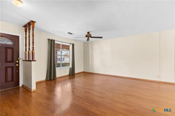 a view of an empty room with a window and wooden floor