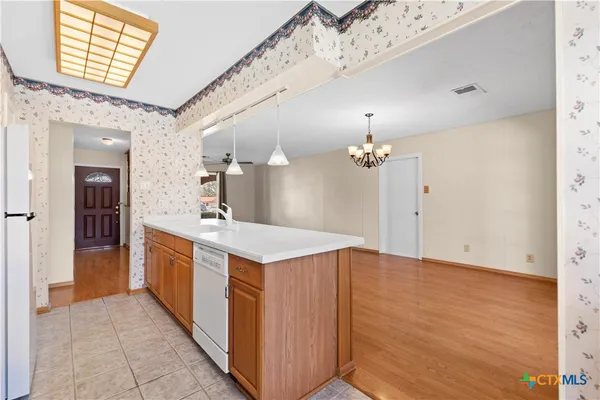 a view of a kitchen with kitchen island a sink hardwood floor and a chandelier