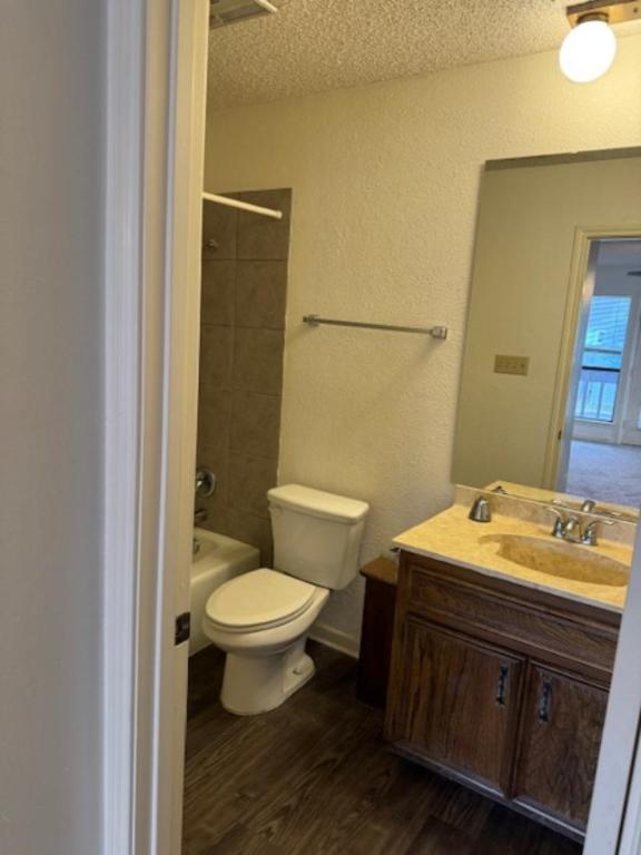 8333 Fathom Circle, Unit B Austin, TX 78750 - Photo 15 of 21 Full bathroom featuring a textured ceiling, vanity, a textured wall, dark wood-style flooring, and shower / washtub combination