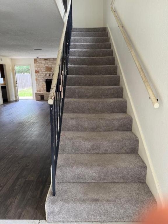8333 Fathom Circle, Unit B Austin, TX 78750 - Photo 17 of 21 Staircase with a fireplace, wood finished floors, and a textured ceiling