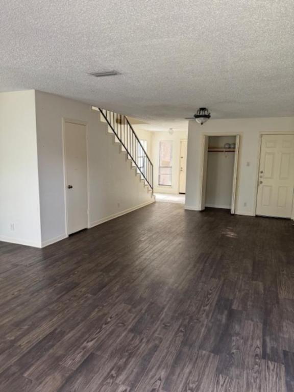 8333 Fathom Circle, Unit B Austin, TX 78750 - Photo 2 of 21 Unfurnished living room with dark wood-style floors, stairway, and a textured ceiling