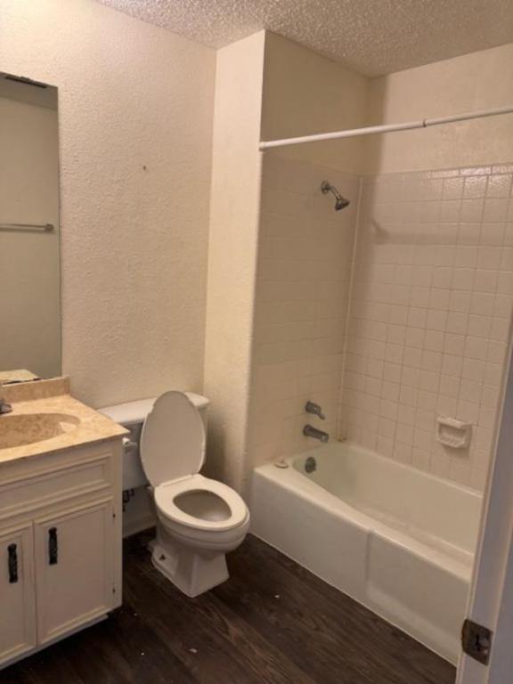 8333 Fathom Circle, Unit B Austin, TX 78750 - Photo 5 of 21 Bathroom with vanity, tub / shower combination, a textured wall, dark wood-style flooring, and a textured ceiling