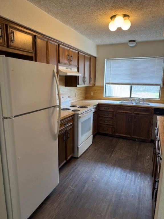 8333 Fathom Circle, Unit B Austin, TX 78750 - Photo 8 of 21 Kitchen with white appliances, light countertops, brown cabinetry, under cabinet range hood, and dark wood-style flooring