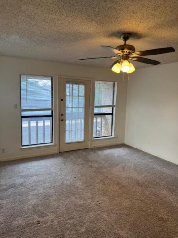 8333 Fathom Circle, Unit B Austin, TX 78750 - Photo 9 of 21 Empty room featuring a textured ceiling, carpet flooring, healthy amount of natural light, and a ceiling fan