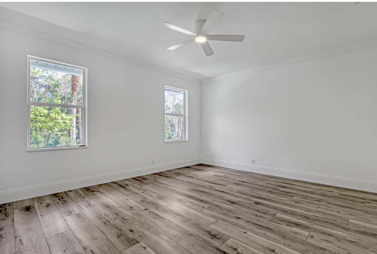 11871 Randolph Siding Road Jupiter, FL 33478 - Photo 38 of 51 an empty room with wooden floor ceiling fan and windows
