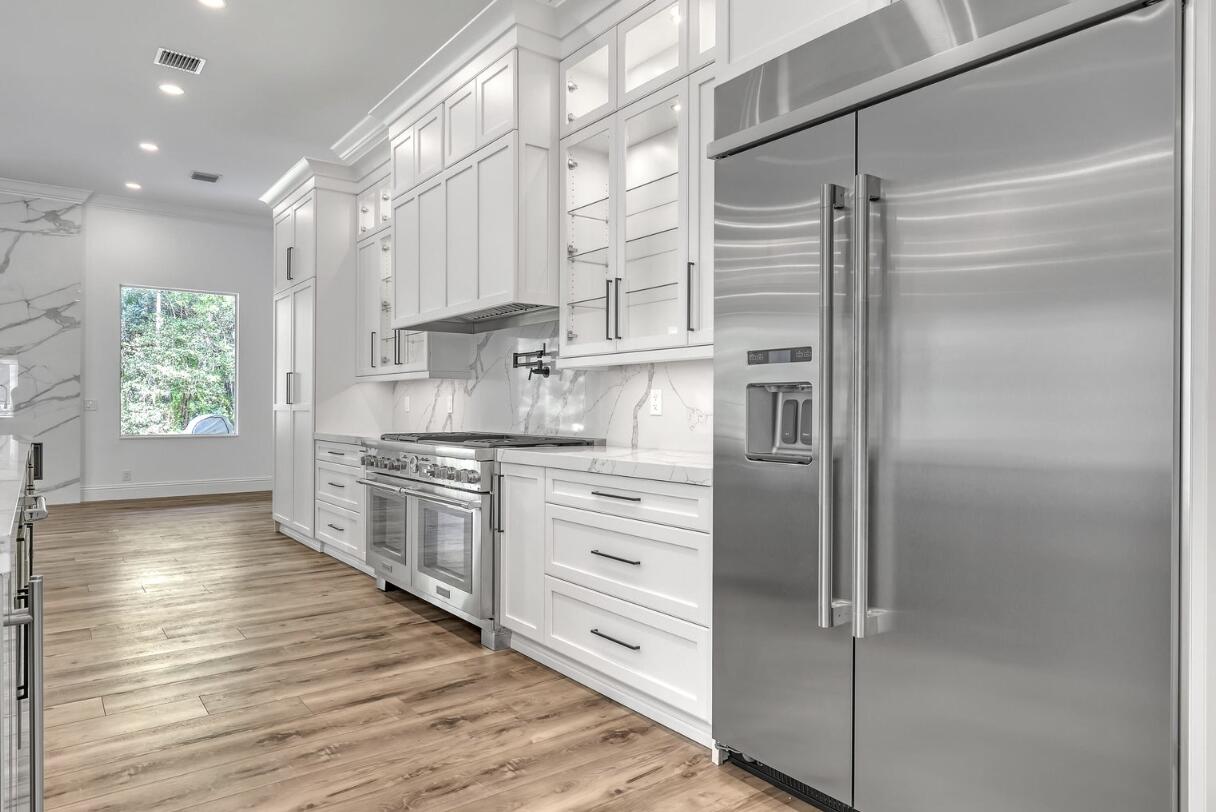 11871 Randolph Siding Road Jupiter, FL 33478 - Photo 7 of 51 a kitchen with stainless steel appliances cabinets a wooden floor and a window