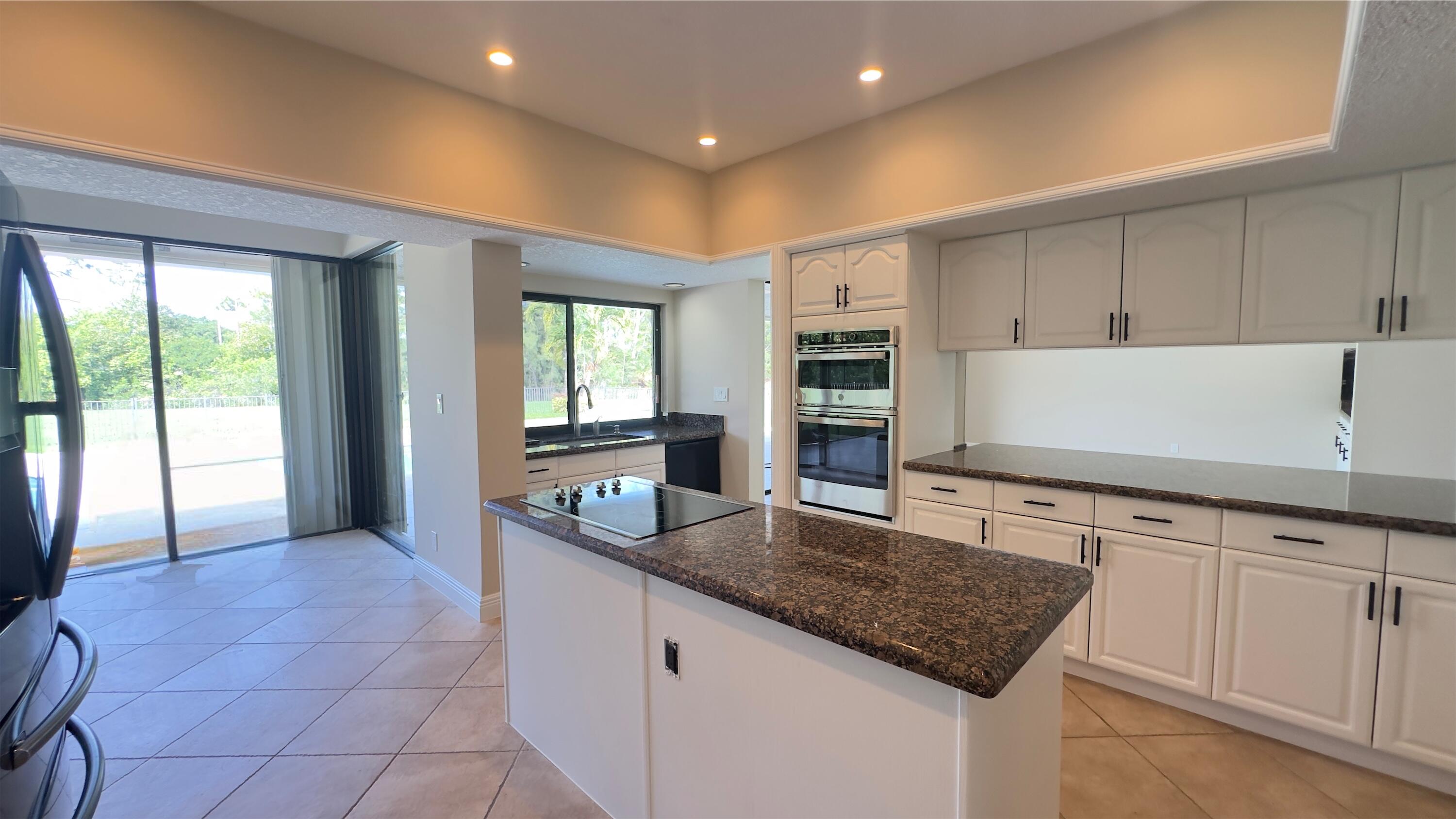 11330 Timber Lodge Terrace Boca Raton, FL 33428 - Photo 8 of 23 a kitchen with kitchen island granite countertop a sink a counter top space and cabinets