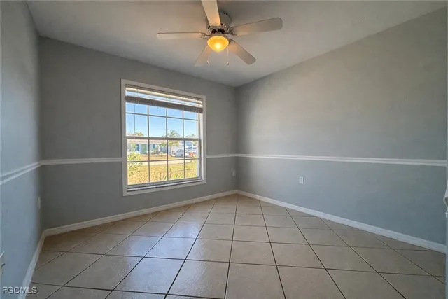 a view of an empty room with window and chandelier fan